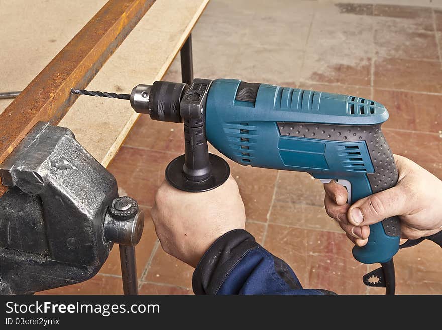 A man drilling a hole in the metallic sheet. A man drilling a hole in the metallic sheet