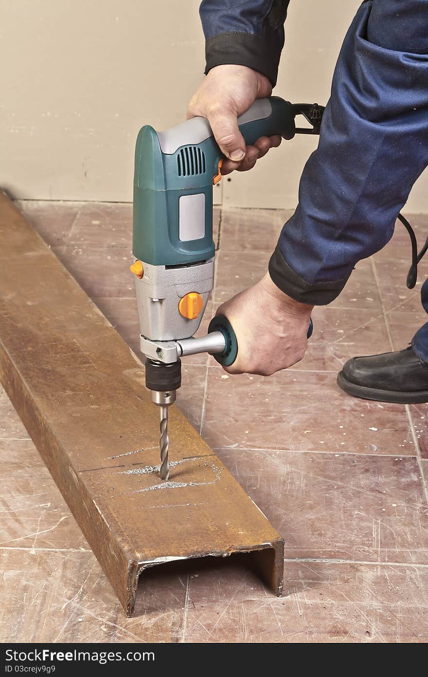 A man drilling a hole in the steel channel. A man drilling a hole in the steel channel