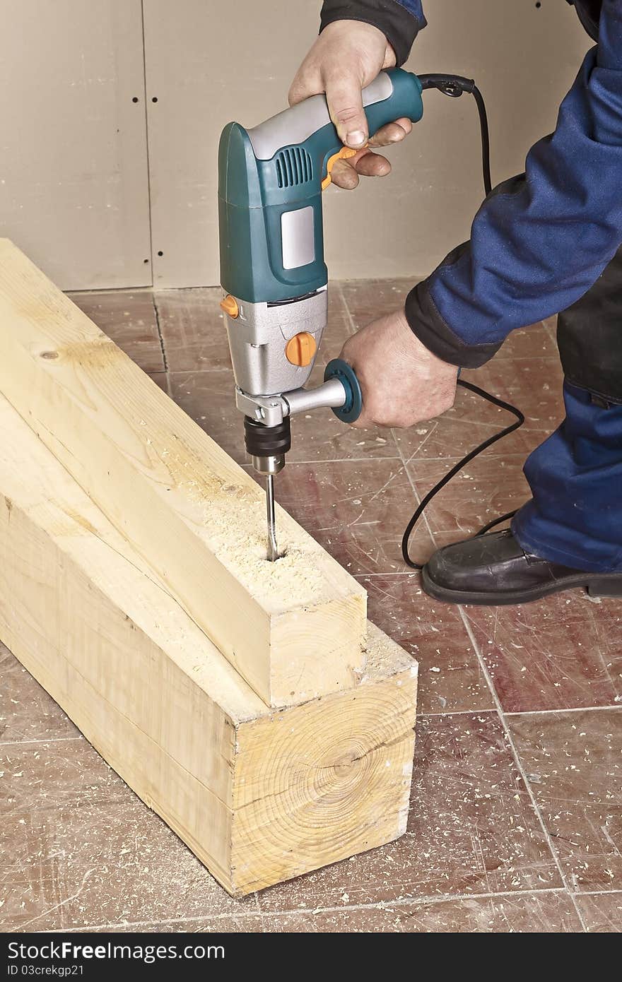 A man drilling a hole in wooden block. A man drilling a hole in wooden block