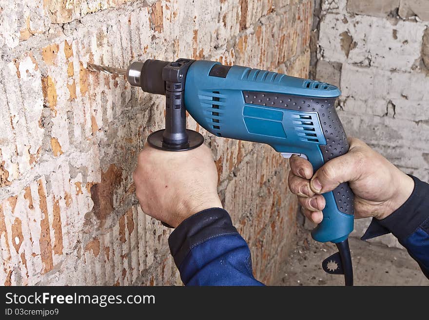 A man drilling a hole in the wall. A man drilling a hole in the wall.