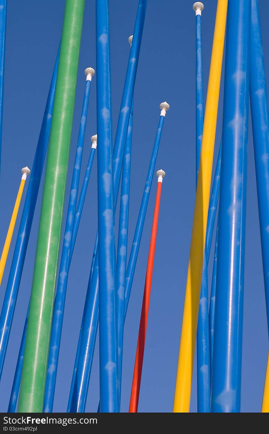 Colorful empty flagpoles against a clear blue sky