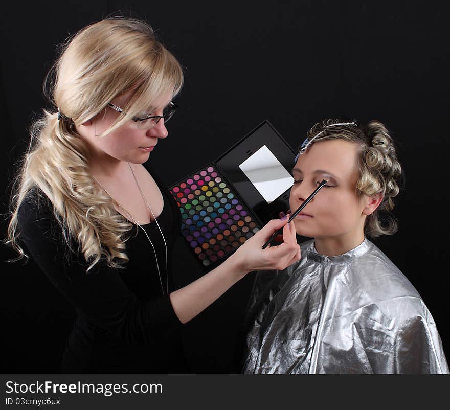 Stylist beautician does her hair and makeup, preparing model shooting