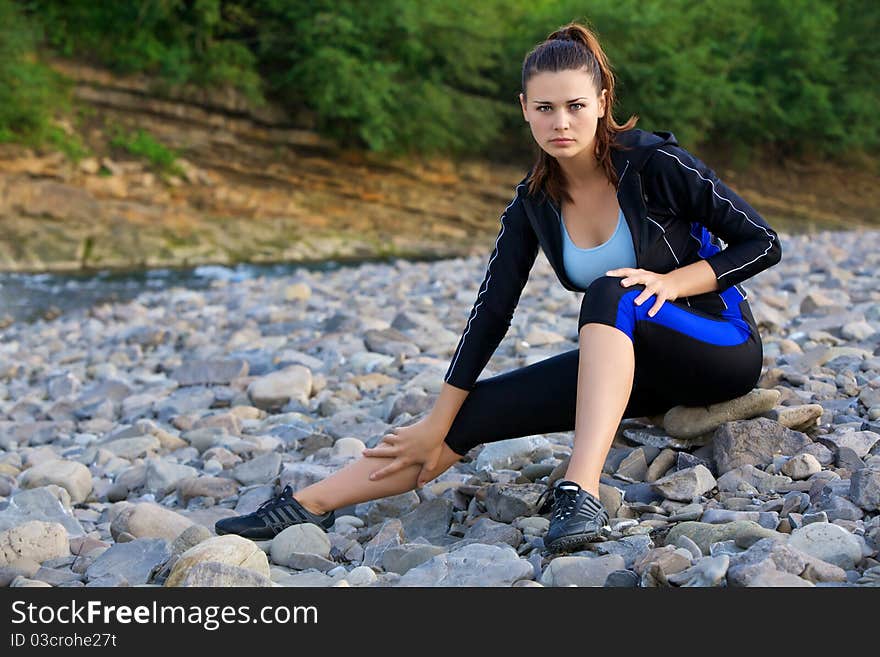 Portrait of the Beautiful young girl in sportswear near the mountain river.