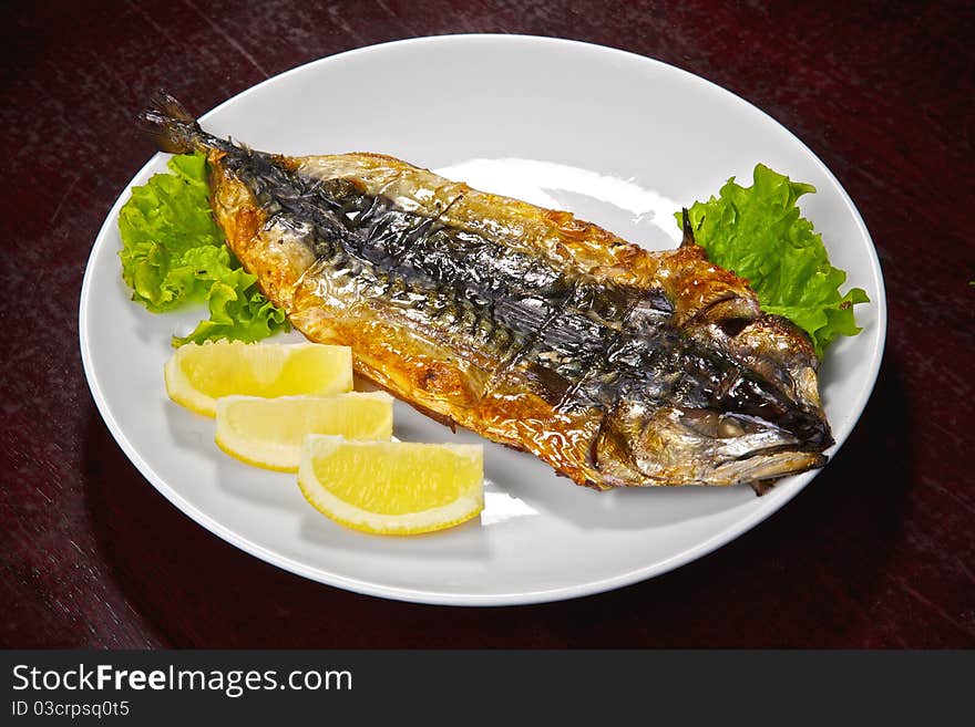 Mackerel on a grill. Fish prepared on fire with a lemon