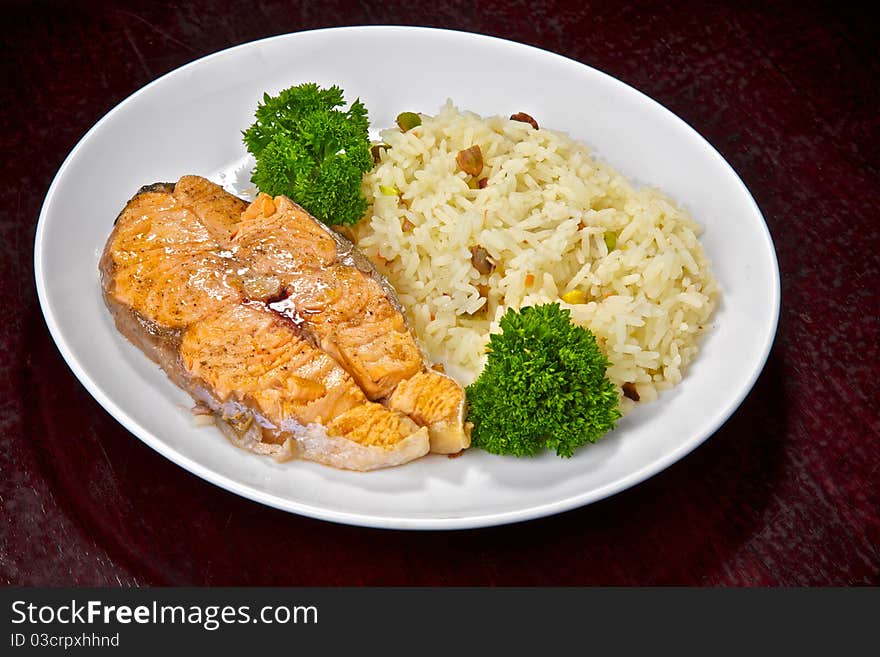 Fillet of a salmon prepared on a grill with a rice garnish and lemon. Fish prepared on fire. Fillet of a salmon prepared on a grill with a rice garnish and lemon. Fish prepared on fire