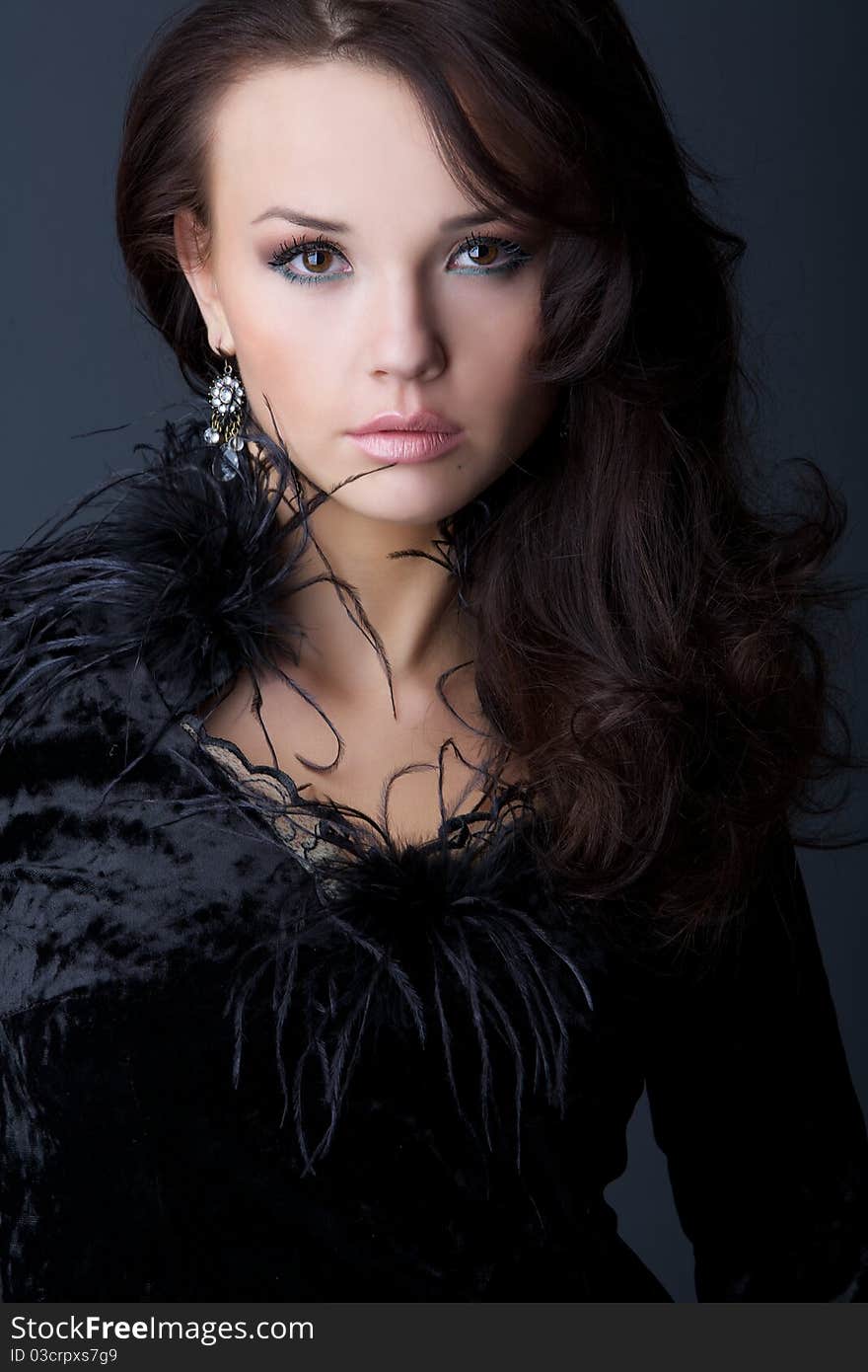 Portrait of the beautiful girl in a black velvet dress with wavy hair.