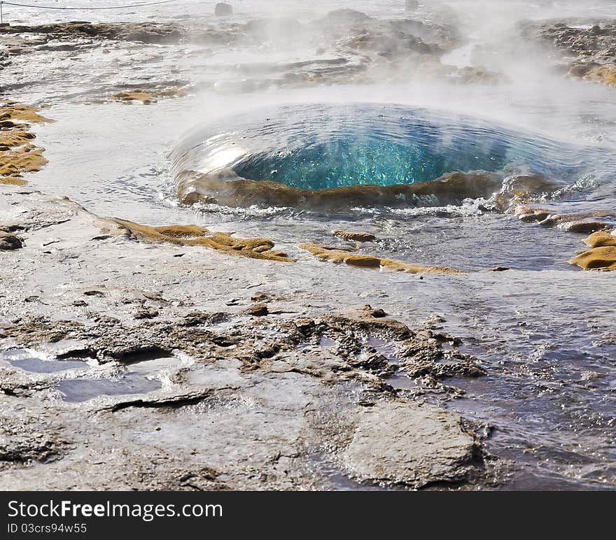 The Geysir, Iceland. A large deep blue bulb of water rises from the little puddle of the Strokkur. The Geysir, Iceland. A large deep blue bulb of water rises from the little puddle of the Strokkur.