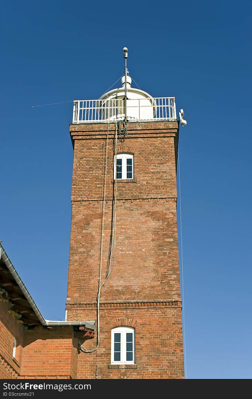 Lighthouse elevation made of red bricks at the blue sky background. Lighthouse elevation made of red bricks at the blue sky background.