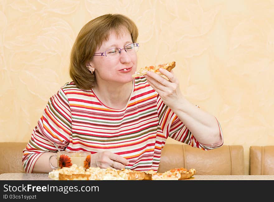 Elderly woman eating pizza at home