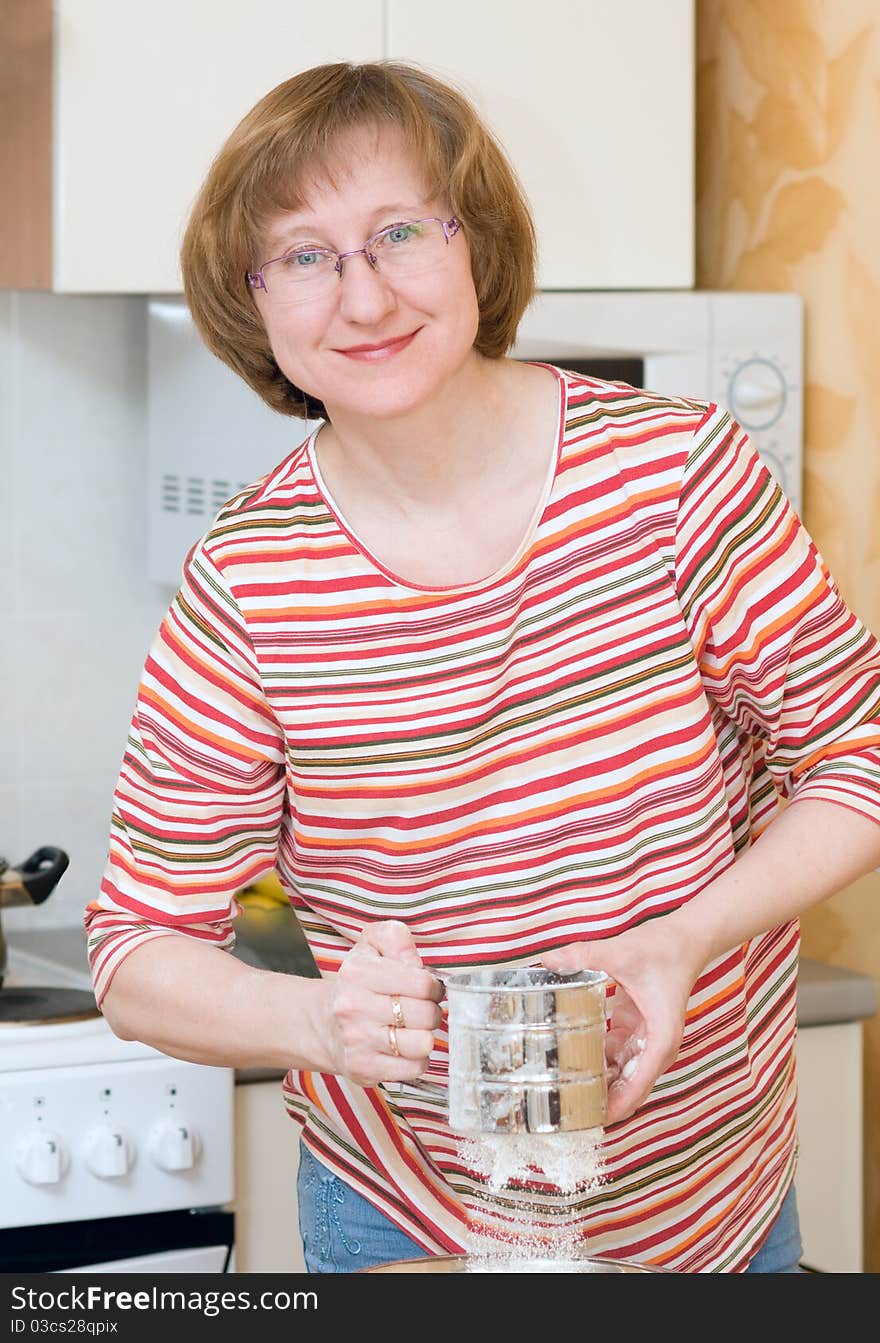 The joyful woman sifts a flour