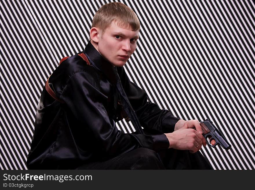 Serious man with a gun against striped background