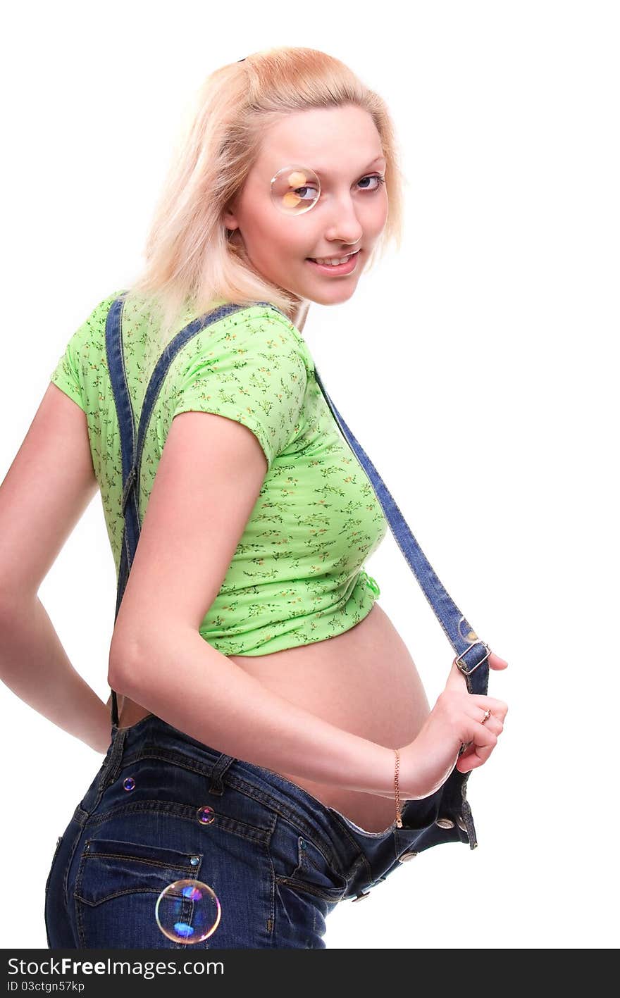 Young pretty pregnant woman posing in jeans overalls