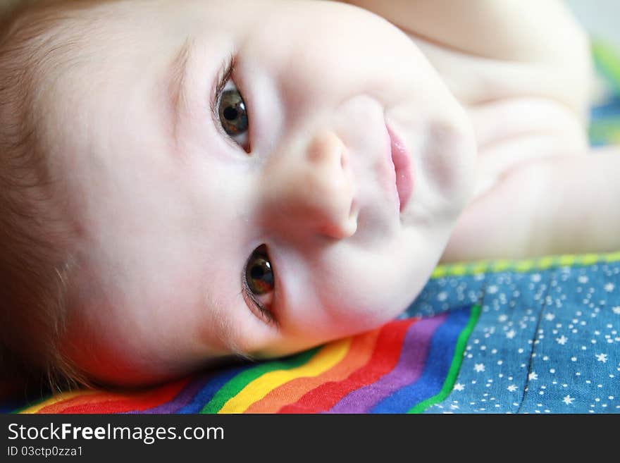 6 month old baby staring right into the camera laying on his handmade blanket.