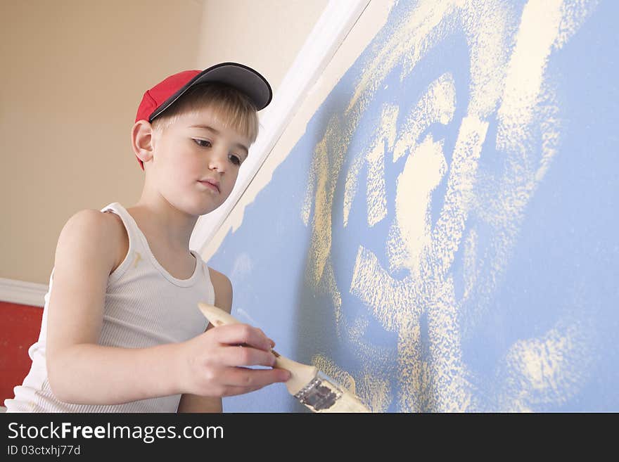 Young boy painting a blue wall with yellowish paint. Young boy painting a blue wall with yellowish paint.