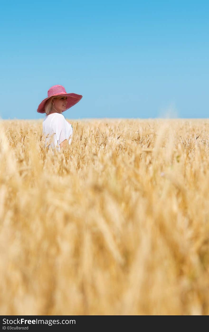 Beautiful woman with hat in wheat meadow on sunny day