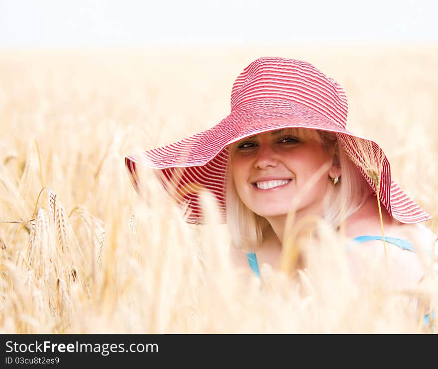 Beautiful woman with hat in wheat meadow on sunny day