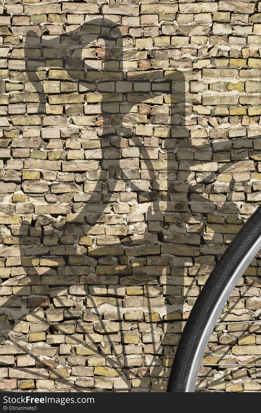 Shadow of a retro race bike on one brick wall with detail view of the wheel in the foreground. Shadow of a retro race bike on one brick wall with detail view of the wheel in the foreground