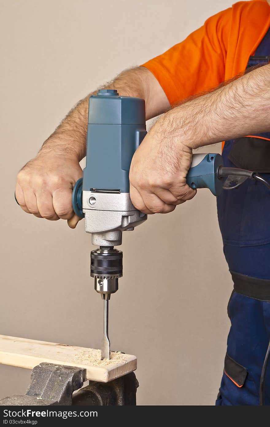 A man drilling a hole in the wooden plank. A man drilling a hole in the wooden plank