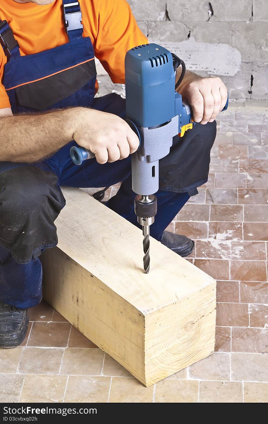 A man drilling a hole in wooden block. A man drilling a hole in wooden block