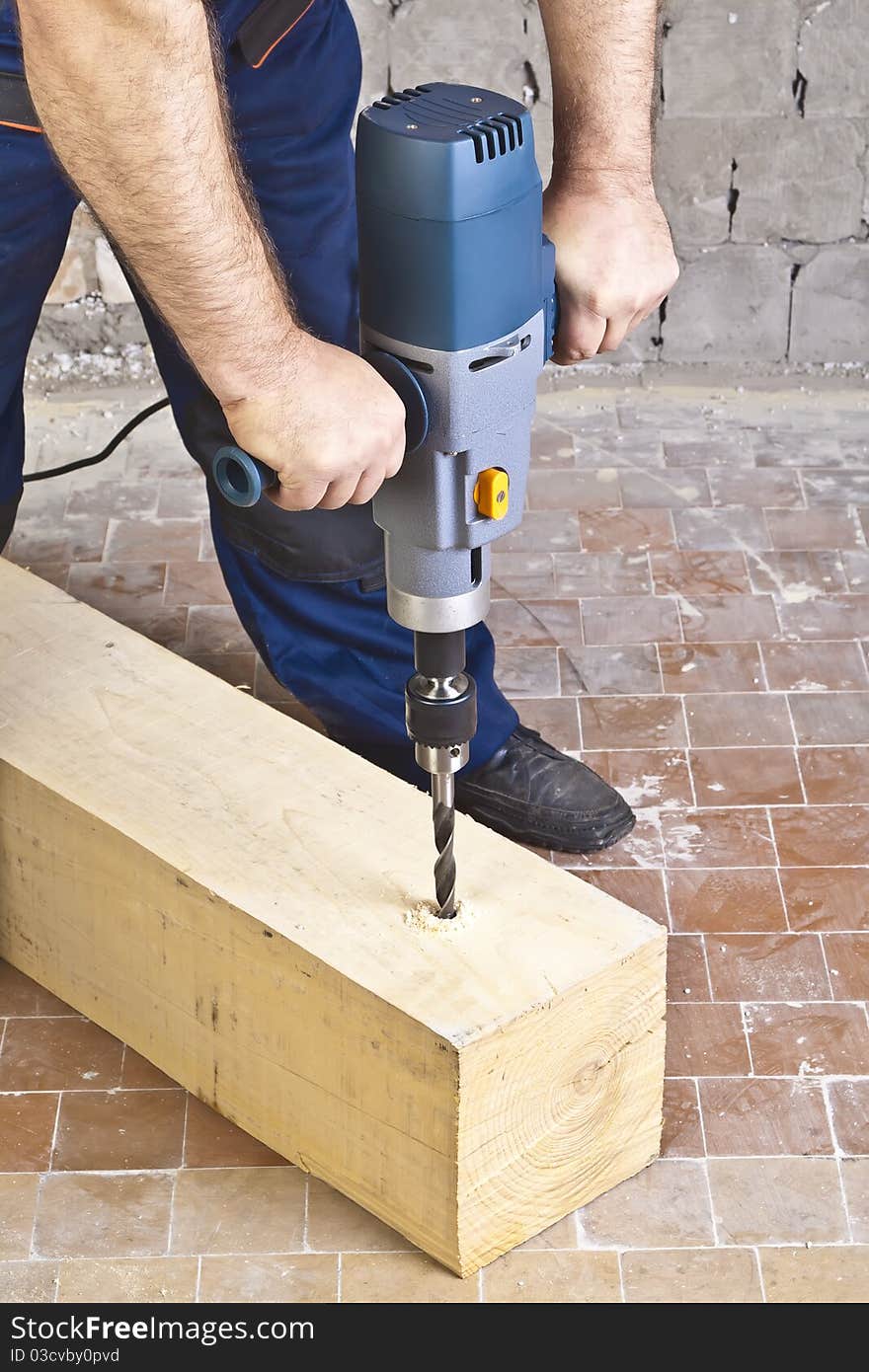 A man drilling a hole in wooden block. A man drilling a hole in wooden block