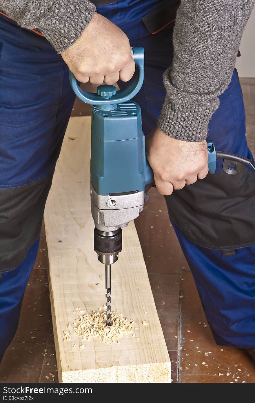 A man drilling a hole in wooden block. A man drilling a hole in wooden block