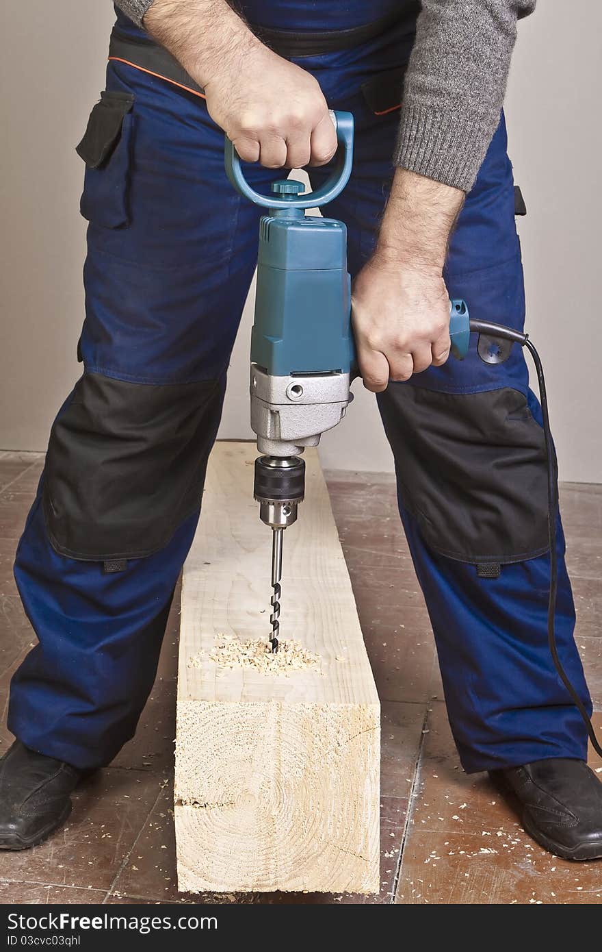 A man drilling a hole in wooden block. A man drilling a hole in wooden block