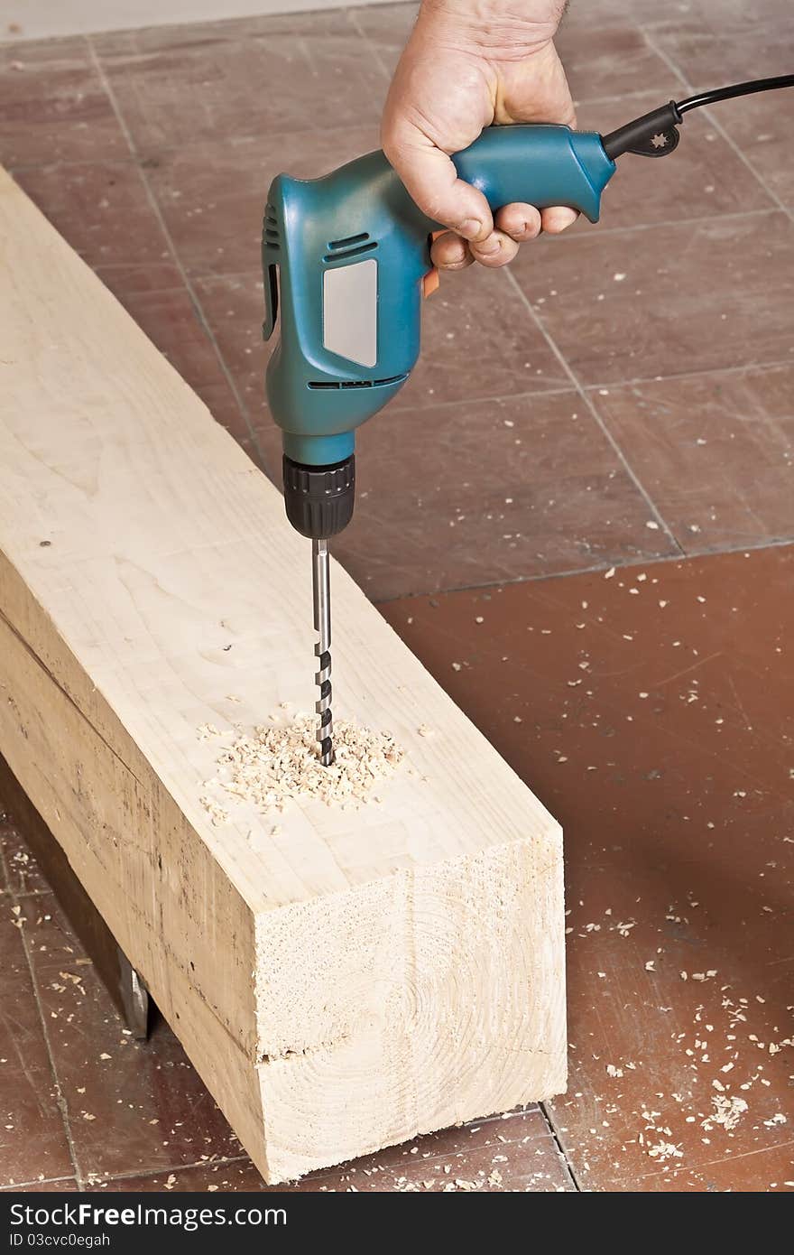 A man drilling a hole in wooden block. A man drilling a hole in wooden block