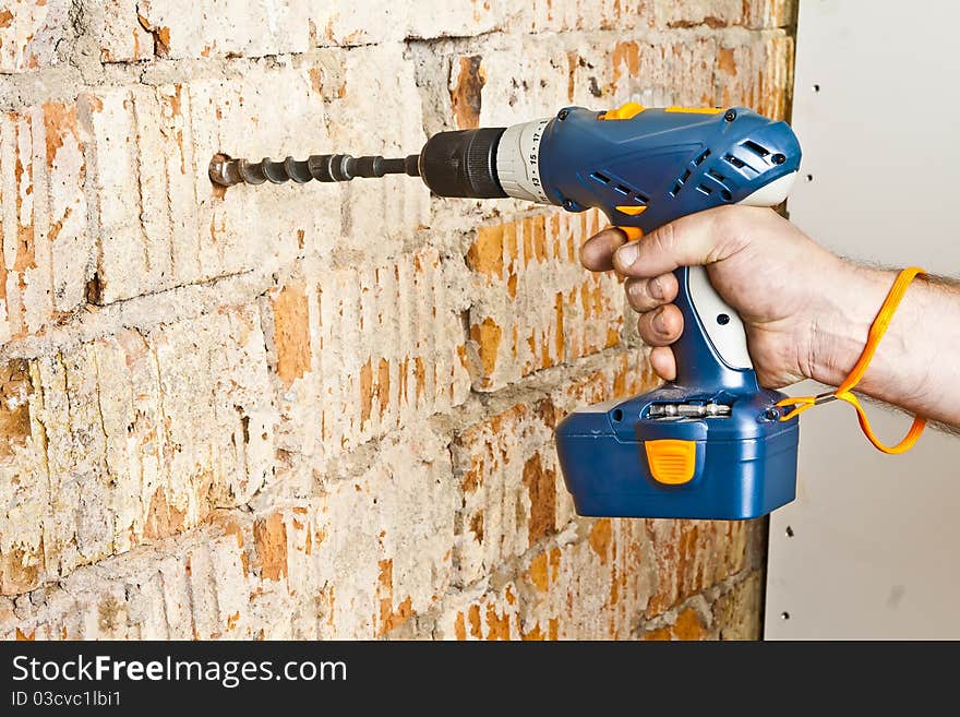 A man drilling a hole in the brick wall. A man drilling a hole in the brick wall.