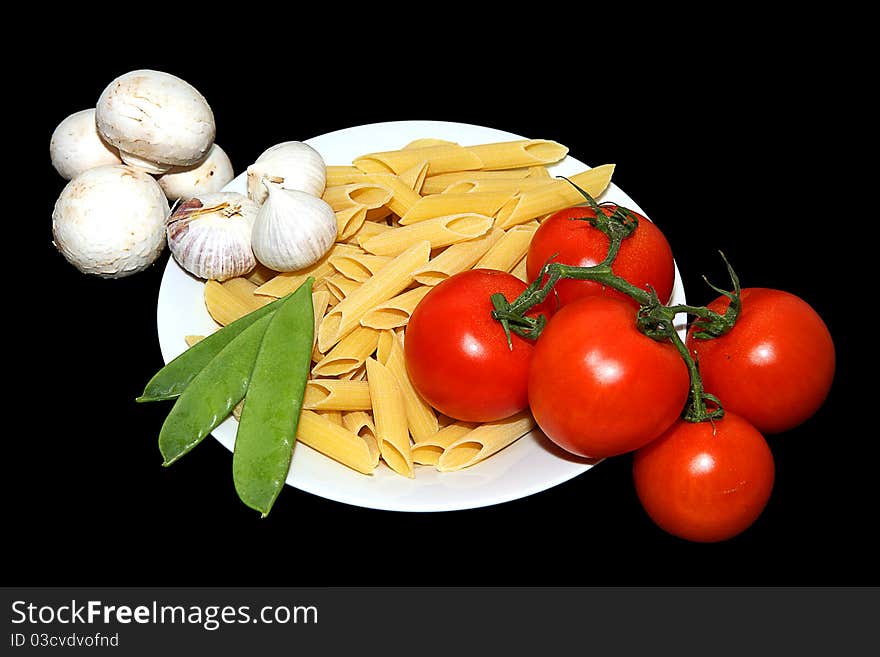 A white plate with pasta tomato garlic and mange tout arranged. A white plate with pasta tomato garlic and mange tout arranged