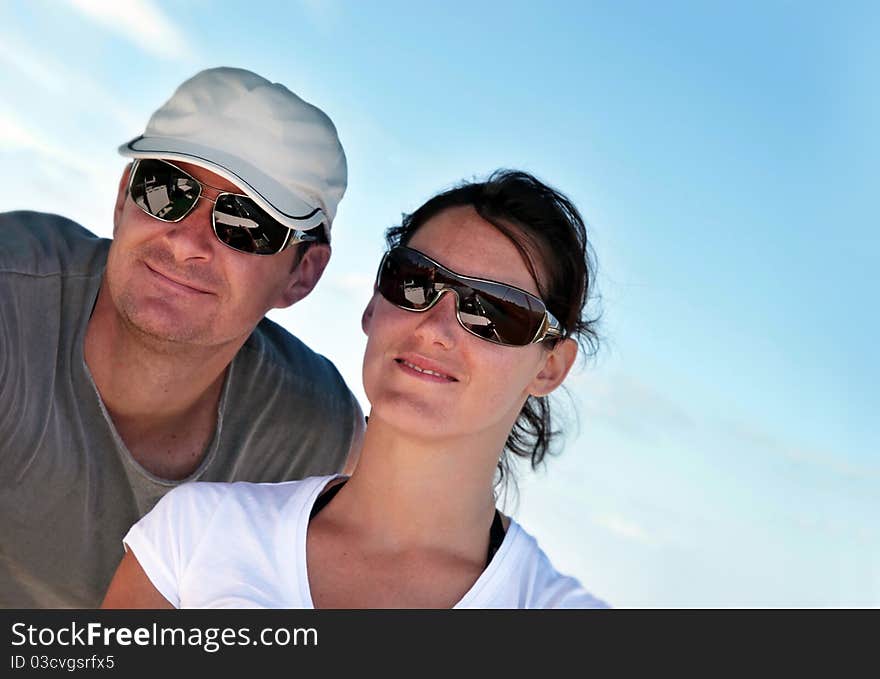 Closeup of a happy young couple on summer vacation, suntanned and wearing sunglasses. Closeup of a happy young couple on summer vacation, suntanned and wearing sunglasses.