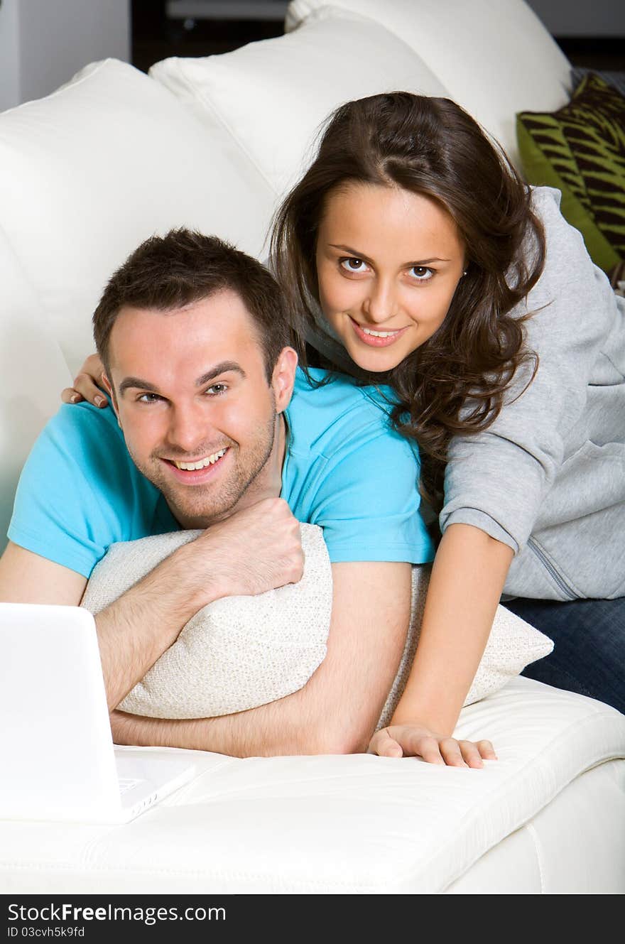 Happy young couple with laptop on white sofa