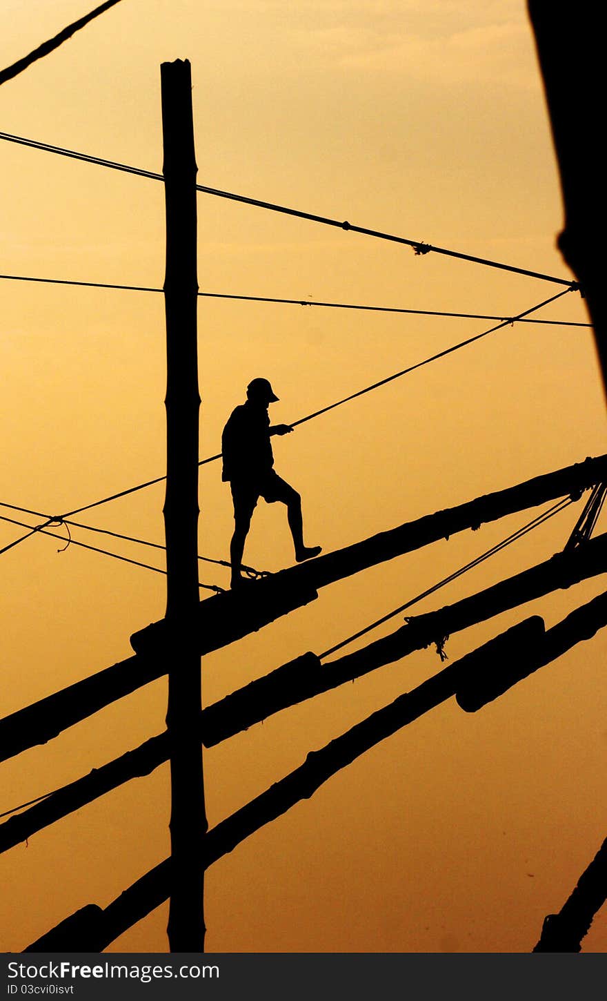 Fisherman walking on a mast in the sunset