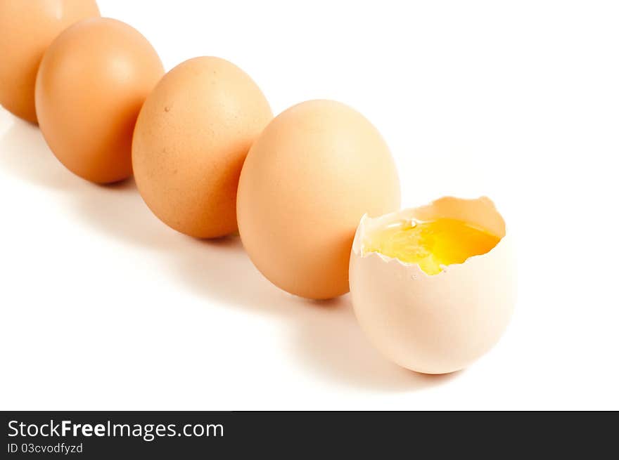 Five eggs standing, one cracked On white background