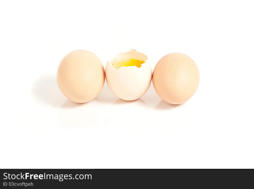 Three eggs standing, one cracked On white background