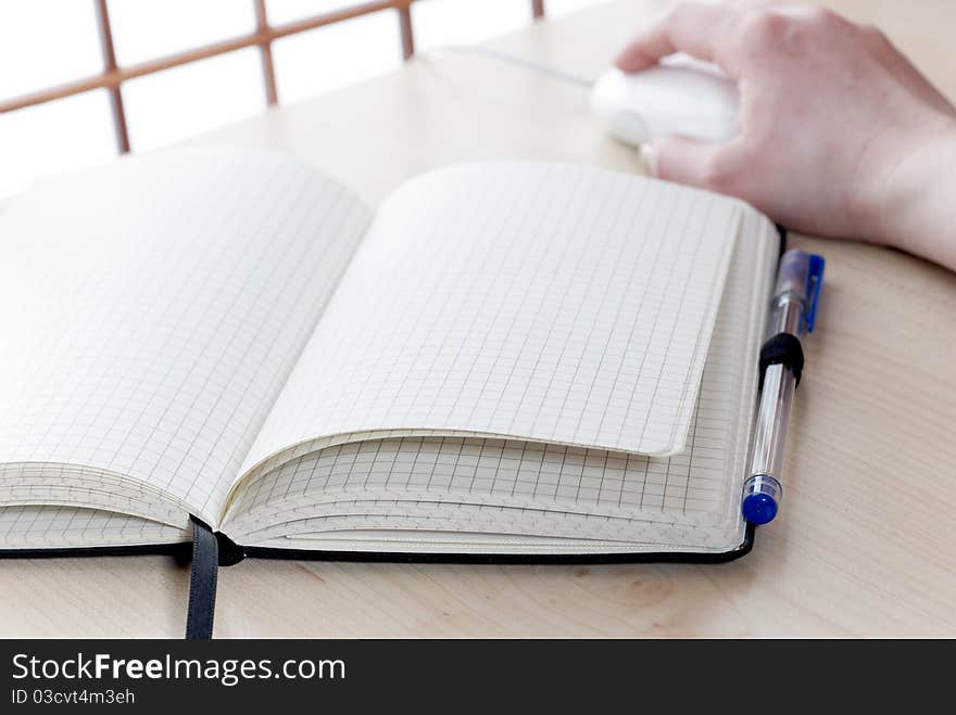 Notebook at a desk with a hand