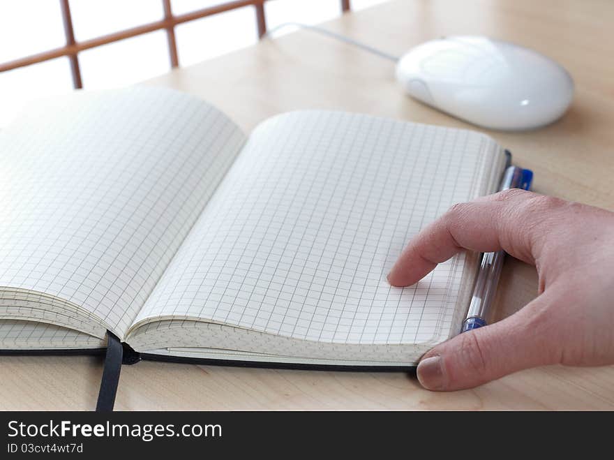 Notebook at a desk with a hand