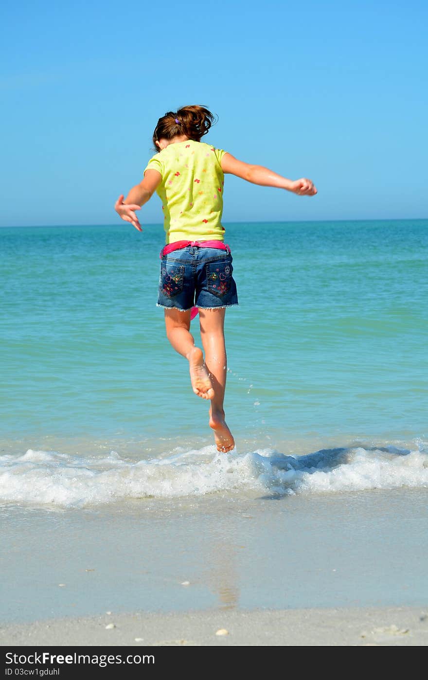 Young girl jumping over waves at the beach. Young girl jumping over waves at the beach