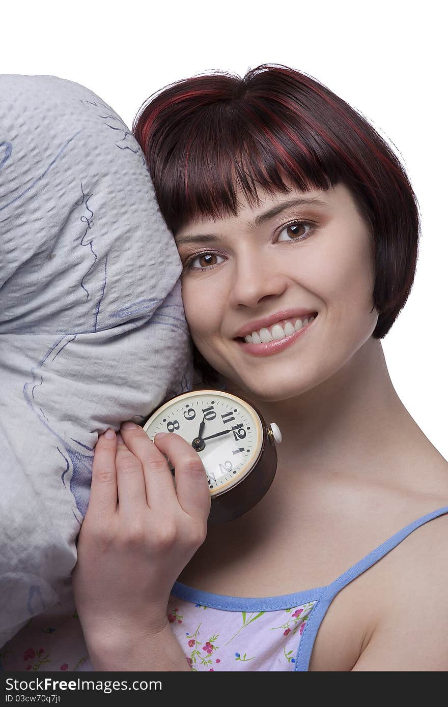 Sleepy woman is holding alarm clock at seven o'clock in the morning. Photo of a young girl waking up in the early morning..