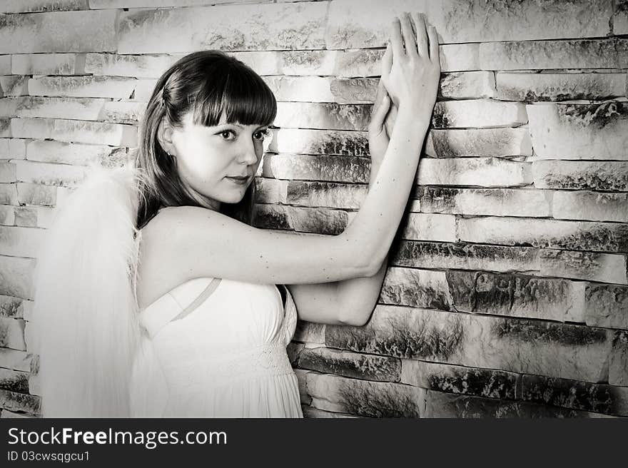 Angel girl on brick wall background. Black and white.