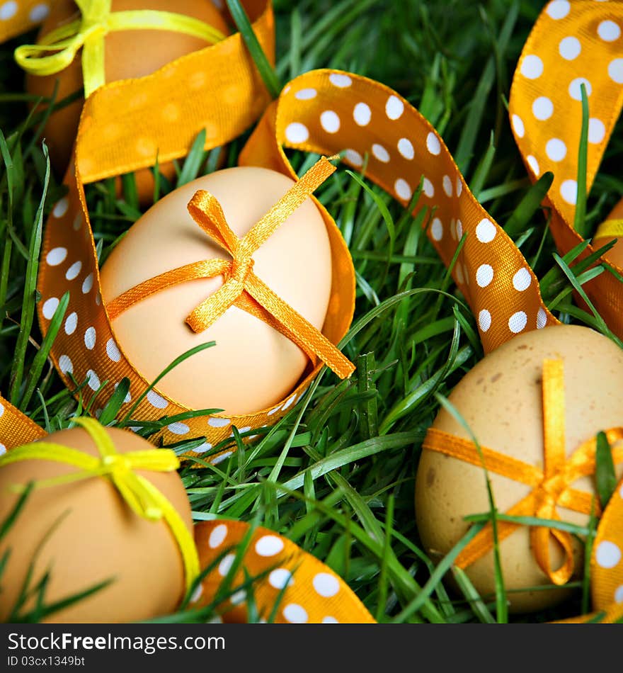 Easter eggs with orange ribbon hidden in the grass. Easter eggs with orange ribbon hidden in the grass