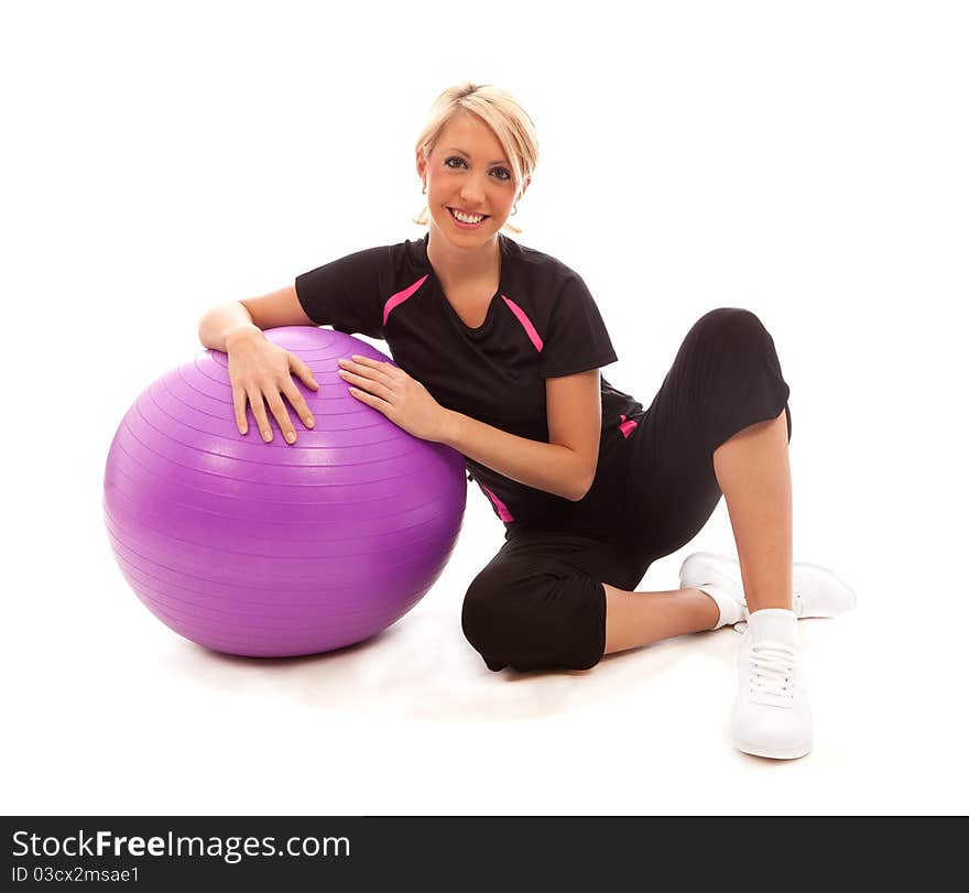 A gril sat on the floor resting a on a purple gym ball. A gril sat on the floor resting a on a purple gym ball