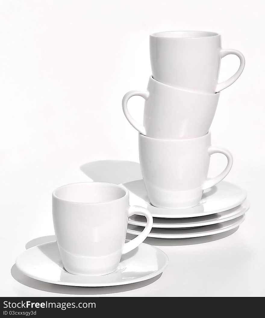 Coffee cups and saucers stacked on white background