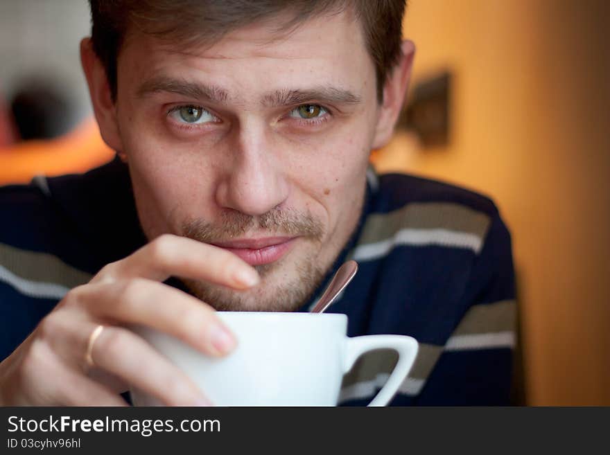 Closeup portrait of a happy young man having a cup of tea