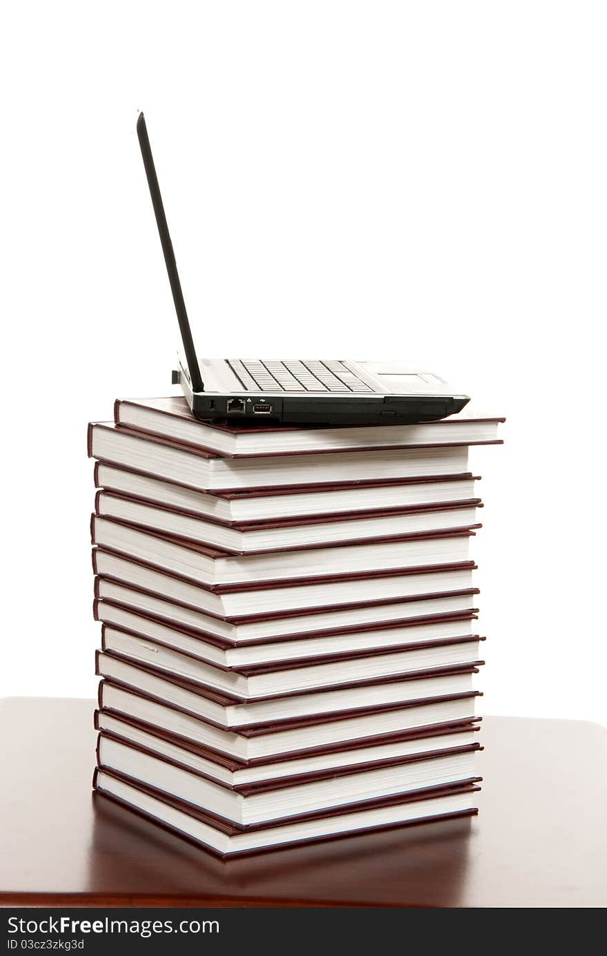 New modern black silver laptop on top of pile of  old educational books on a white background. New modern black silver laptop on top of pile of  old educational books on a white background.