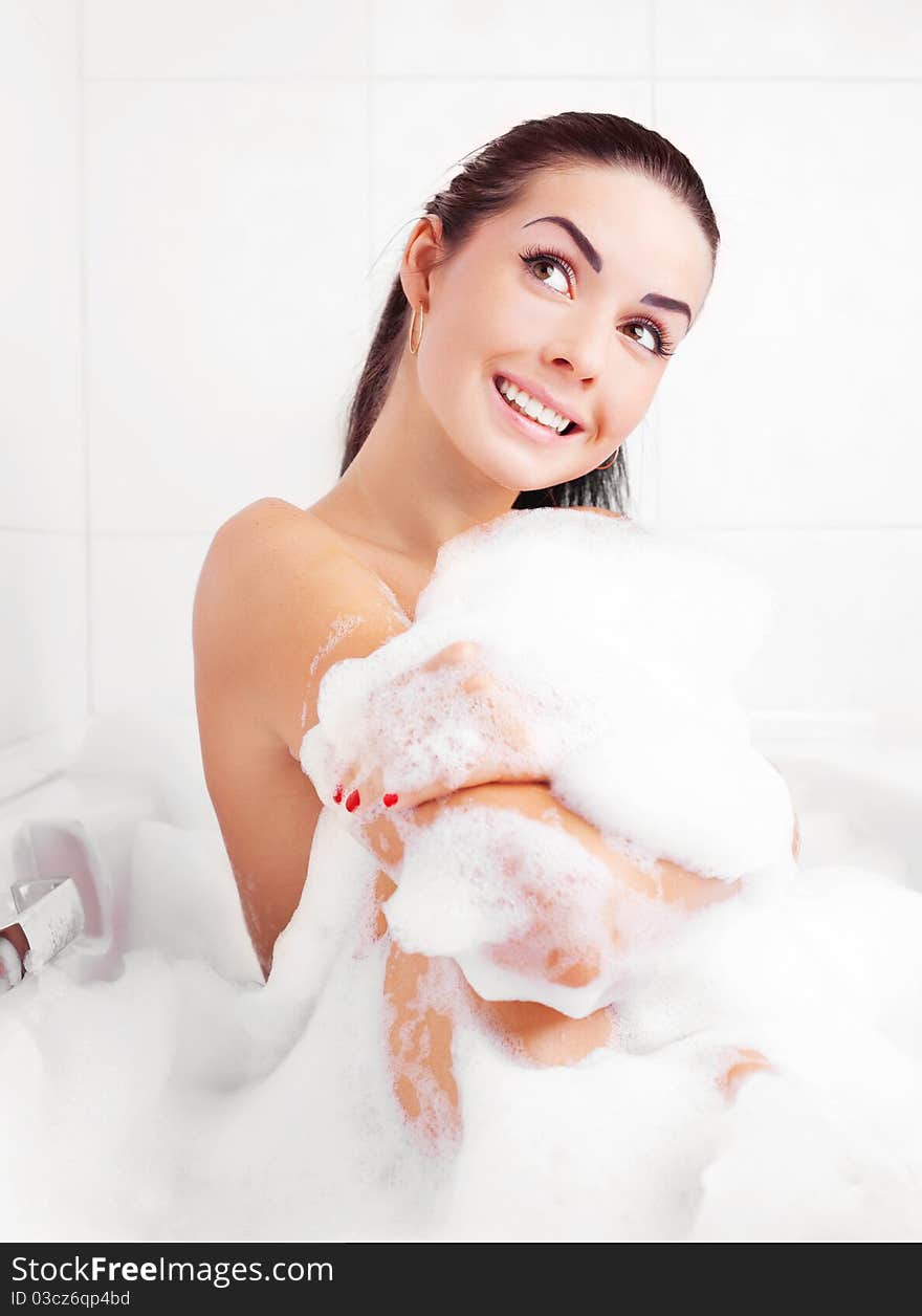 Beautiful young brunette woman taking a relaxing bath with foam. Beautiful young brunette woman taking a relaxing bath with foam