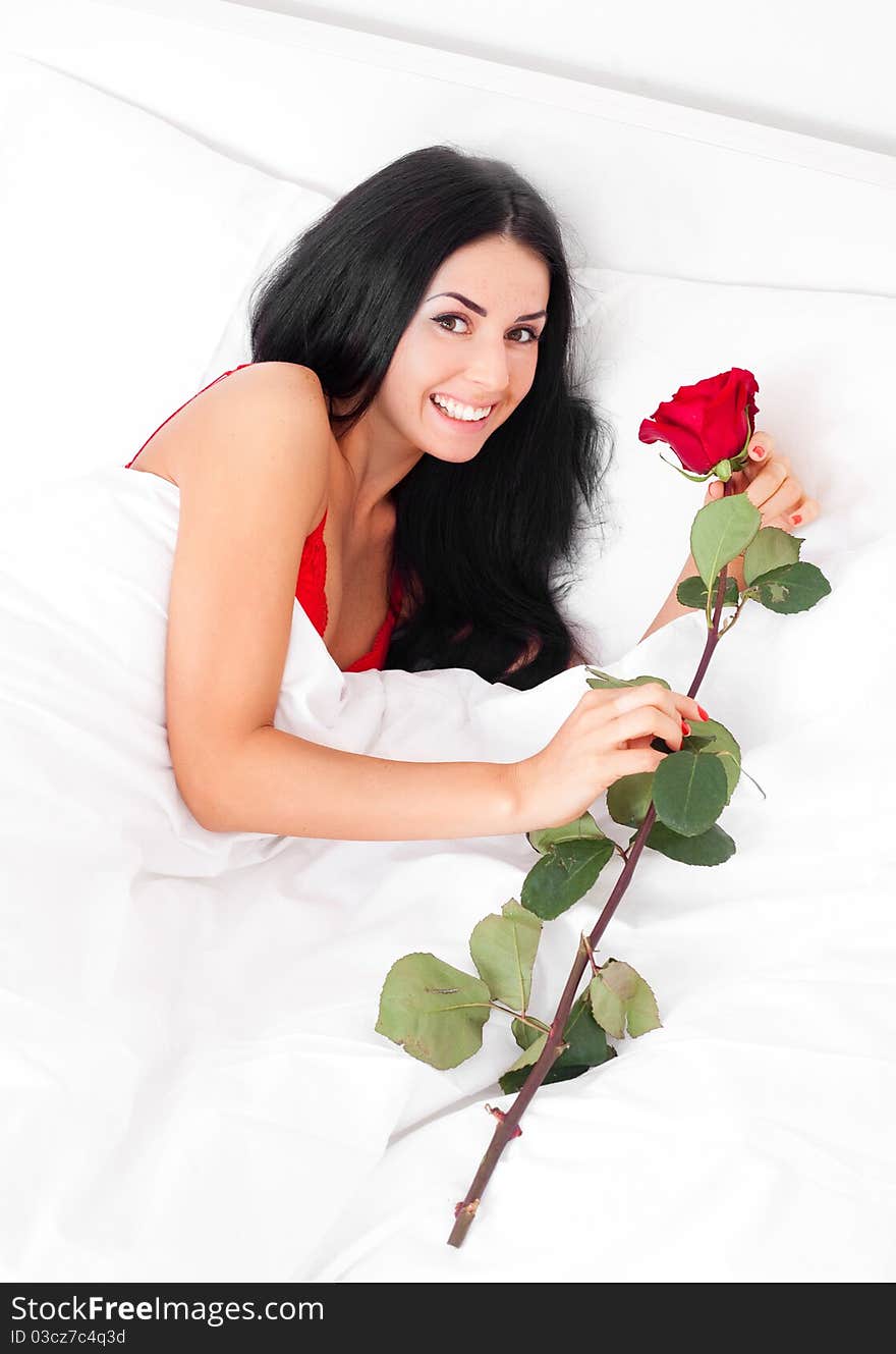 Beautiful brunette woman wakes up and finds a rose in her bed. Beautiful brunette woman wakes up and finds a rose in her bed