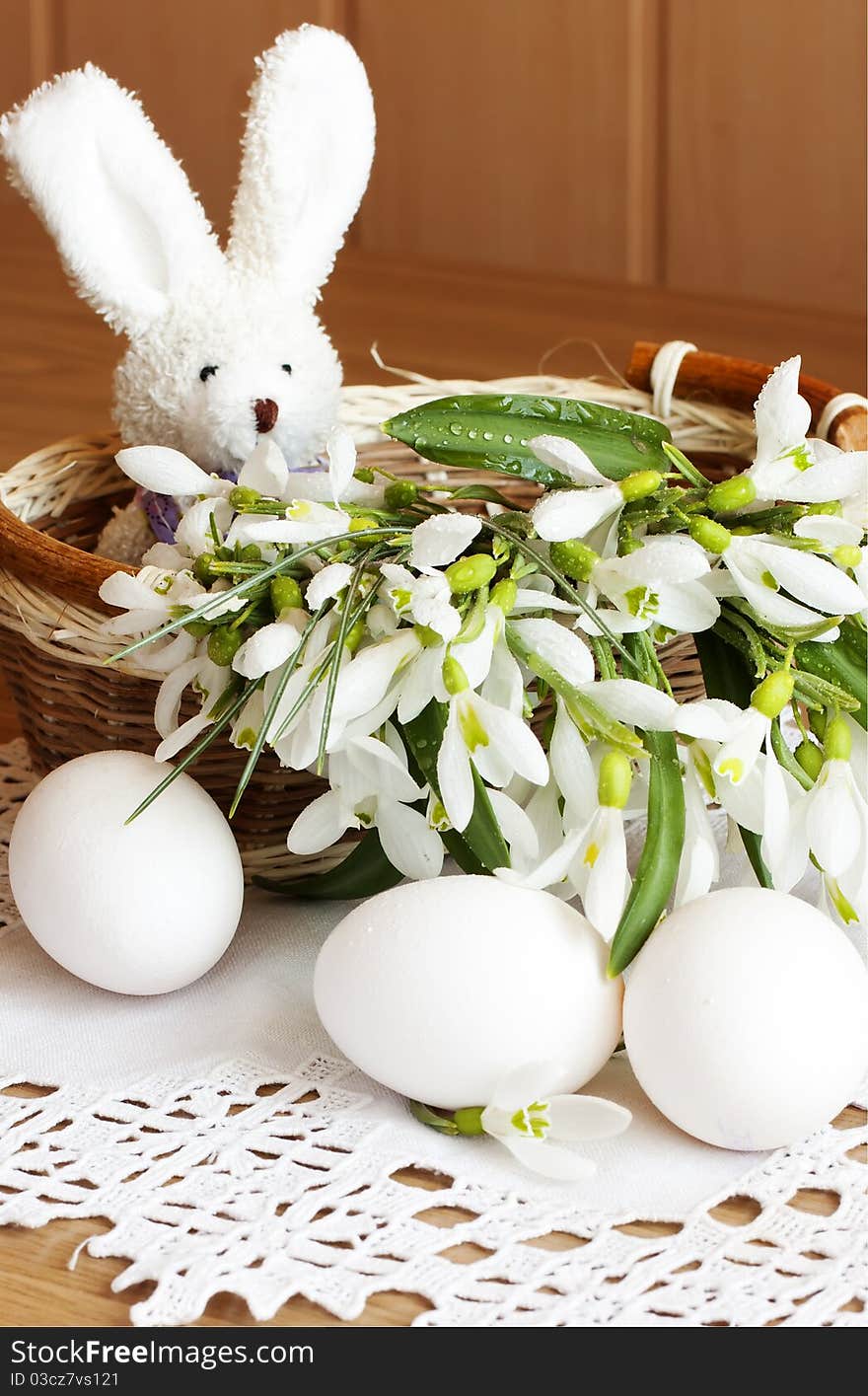 Toy rabbit, eggs and snowdrops in a basket