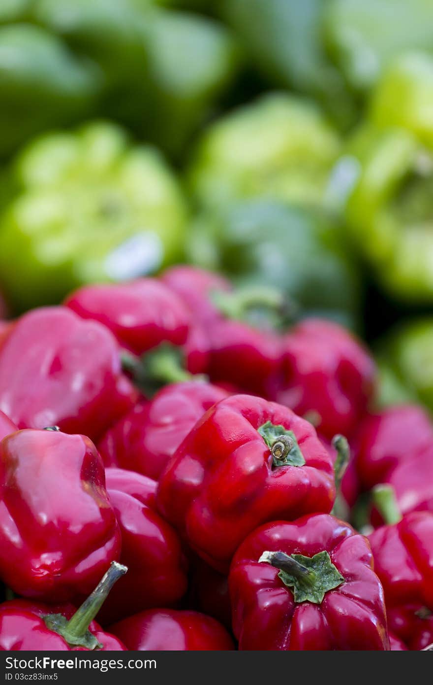 Red Peppers on the foreground and green ones as a blurry background.