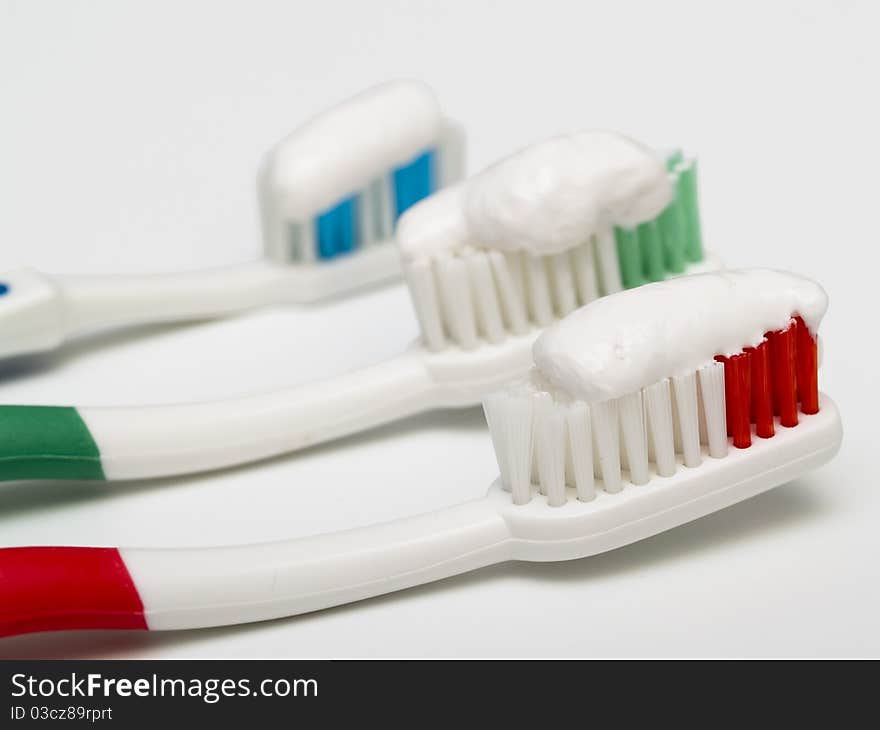 Three colorful toothbrushes with toothpaste