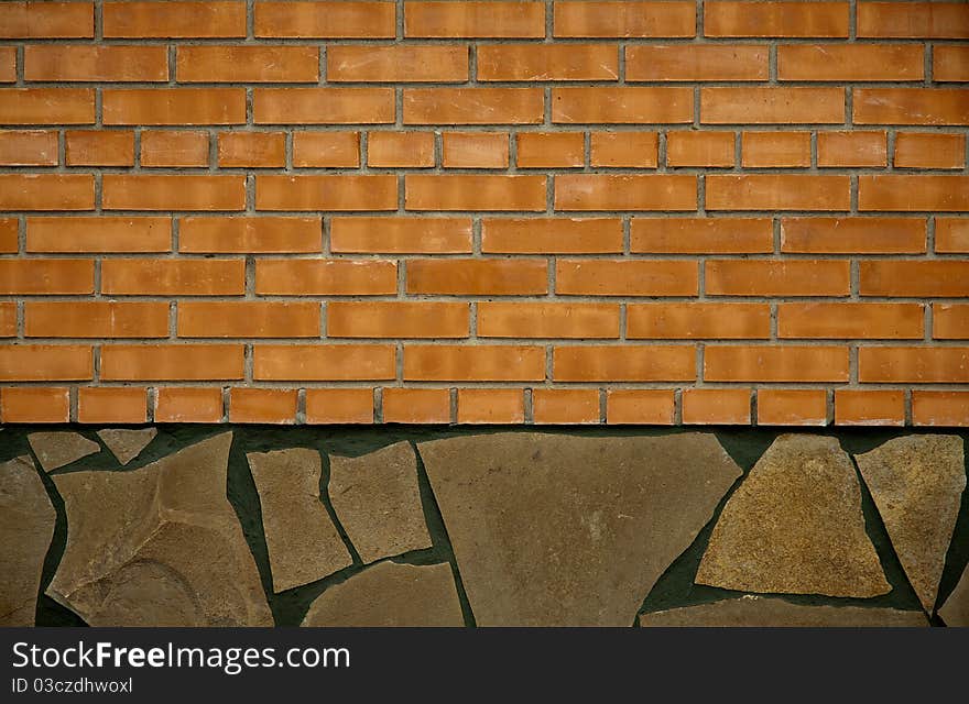 A wall of orange brick partially lined with a flat stone. A wall of orange brick partially lined with a flat stone